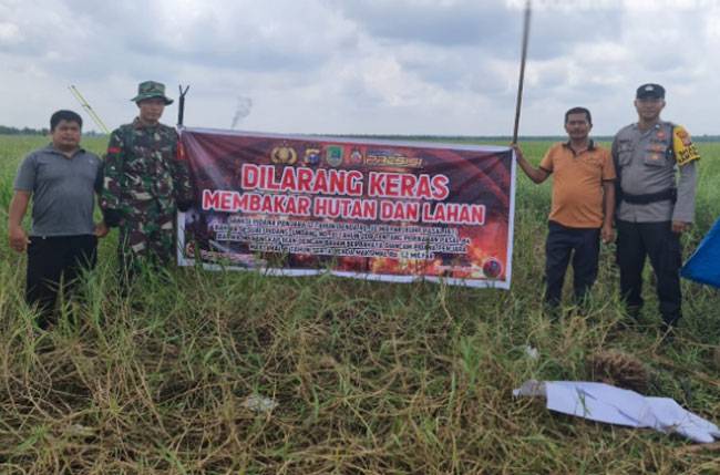 Babinsa 0321-05/RM Dan Bhabinkamtibmas Pasang Spanduk Bahaya Karhutla Di Pematang Damar