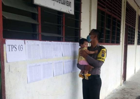Pilkades Serentak, Polisi di Kepulauan Meranti Ini Bantu Gendong Bayi Saat Ibunya Nyoblos