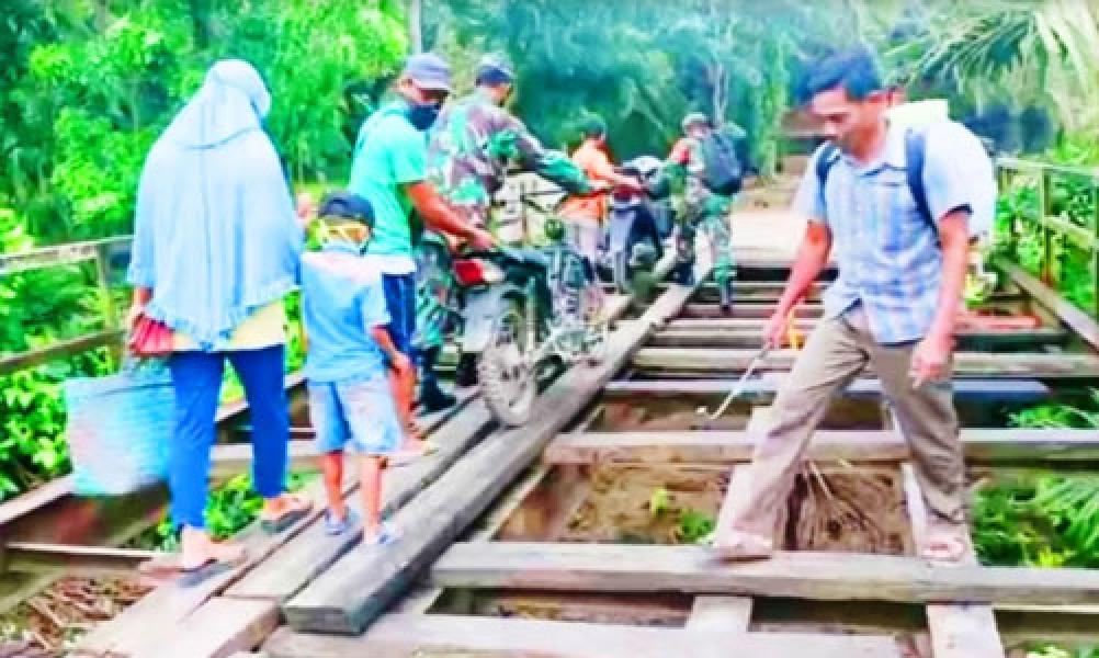 Jembatan Rusak, Babinsa TNI Bantu Seberangkan Warga